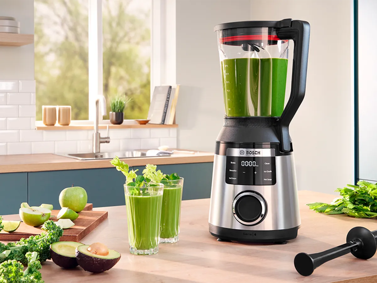 Liquidificador de aço inoxidável VitaPower Serie 6 com smoothies e pratos ao redor em uma prateleira da cozinha.