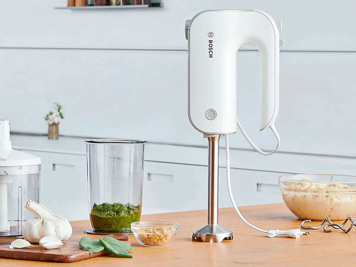 Liquidificador de mão Bosch com vários acessórios sobre uma bancada de cozinha, pronto para tarefas de picar, misturar e bater.