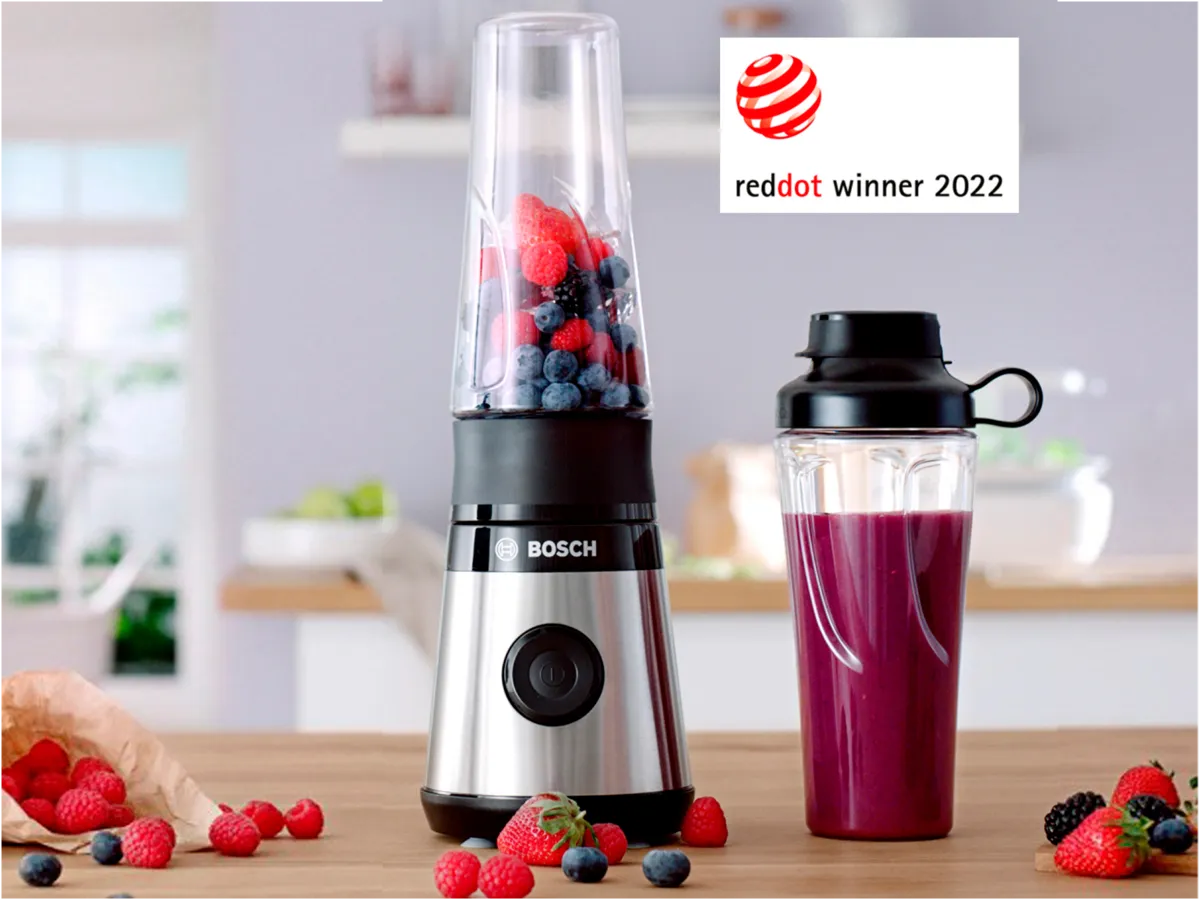Liquidificador Bosch cheio de frutas vermelhas frescas ao lado de uma garrafa de smoothie, exibindo o selo de Vencedor do Prêmio Red Dot 2022.