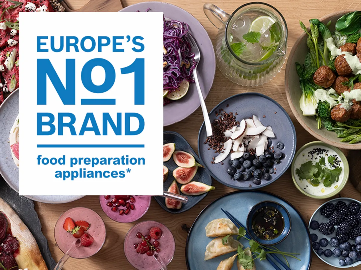 Uma caixa de texto com as palavras "A marca número 1 da Europa em eletrodomésticos de preparação de alimentos" é sobreposta a diferentes pratos de comida sobre uma mesa.