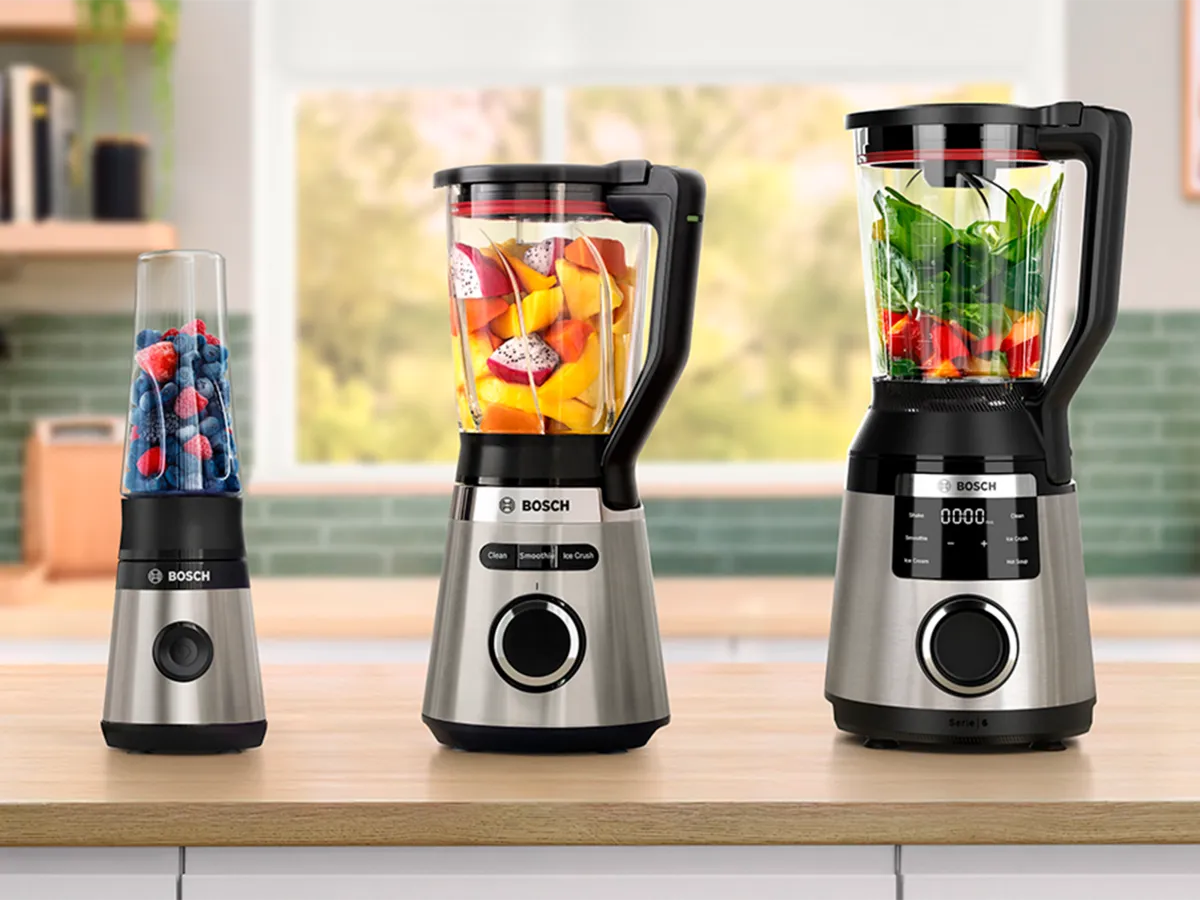 Três liquidificadores Bosch sobre uma bancada de cozinha, cada um preenchido com frutas e legumes vibrantes, destacando seu design elegante e funcionalidade.