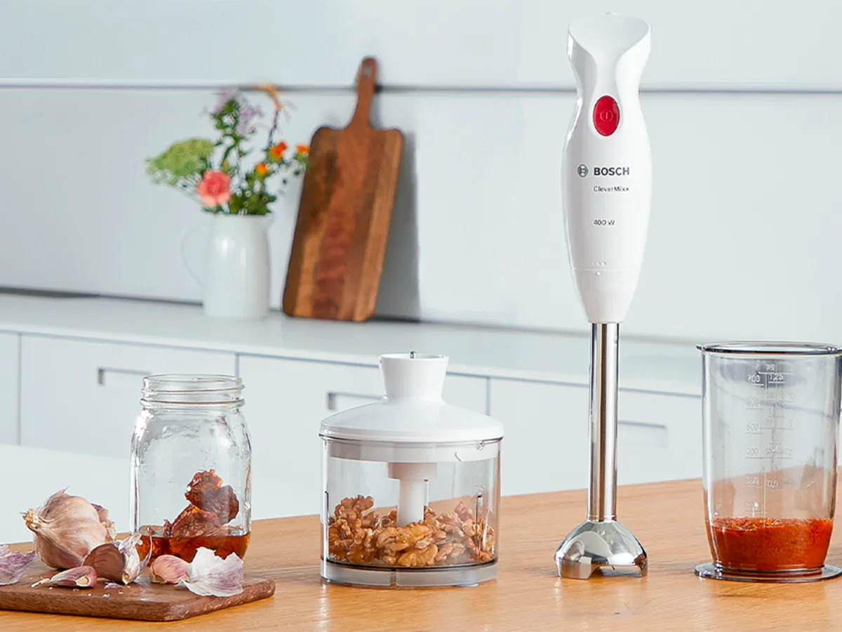 A CleverMixx hand blender clustered with its accessories on a counter in a bright, white kitchen.