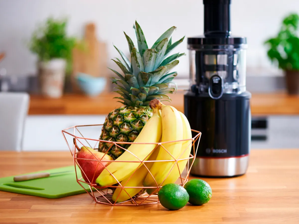 Um cesto de frutas em frente ao espremedor Bosch.