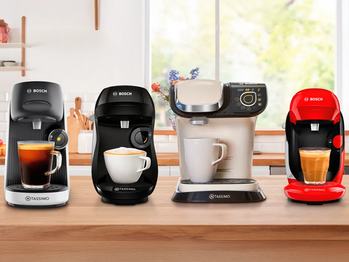 Four different Tassimo coffee machine models on kitchen counter.