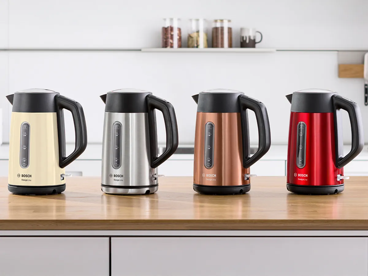 Chaleiras DesignLine sobre uma bancada de cozinha em bege, aço inoxidável, cobre e vermelho.