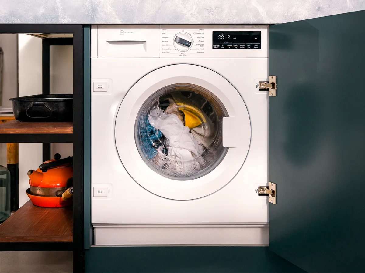 Vollintegrierbare Einbauwaschmaschine von NEFF in moderner Küche – leises Einbaugerät mit 8 kg Fassungsvermögen, eingebaut hinter dunkler Möbelfront.