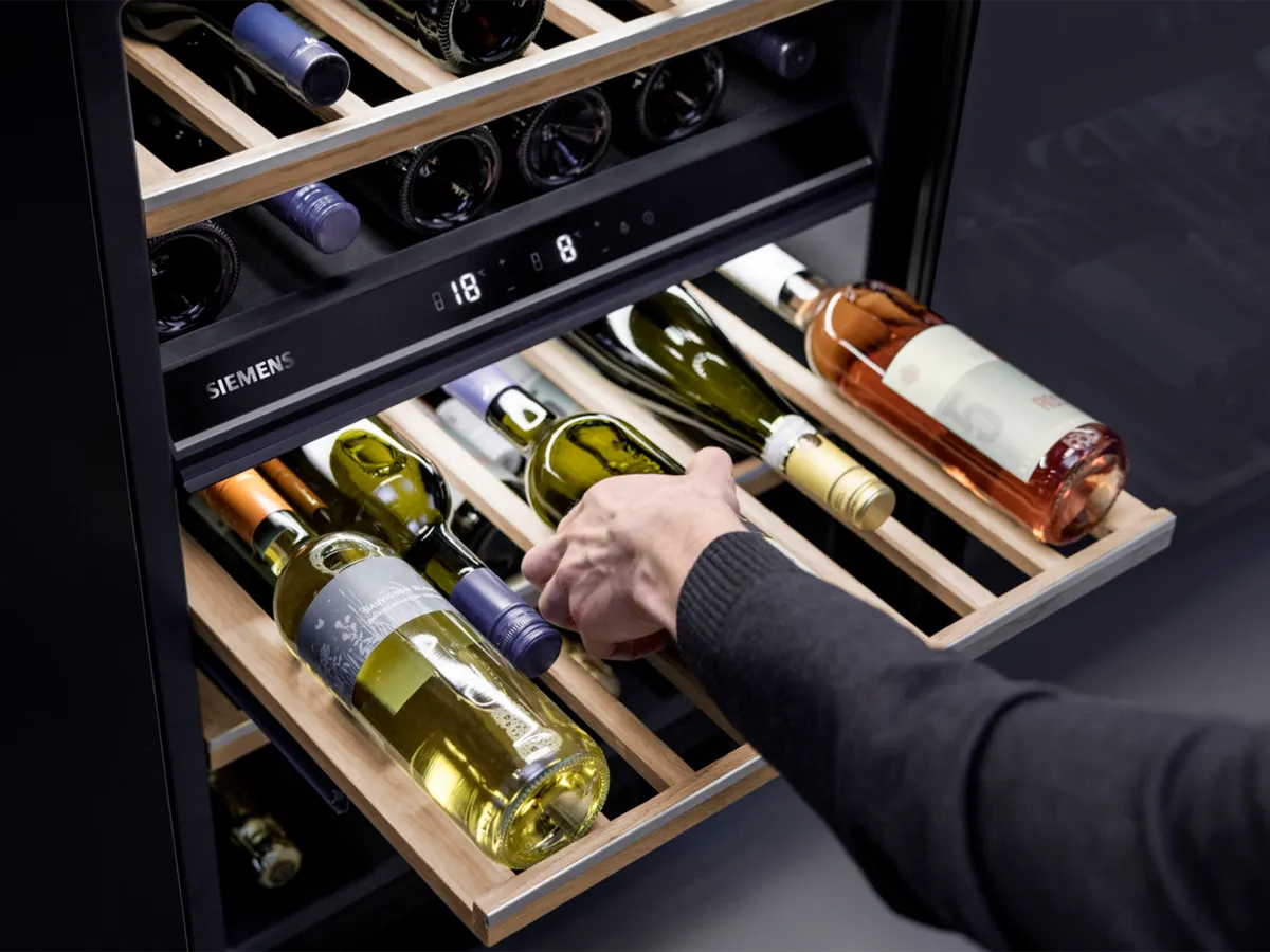 Person taking a bottle of wine out of wine cooler