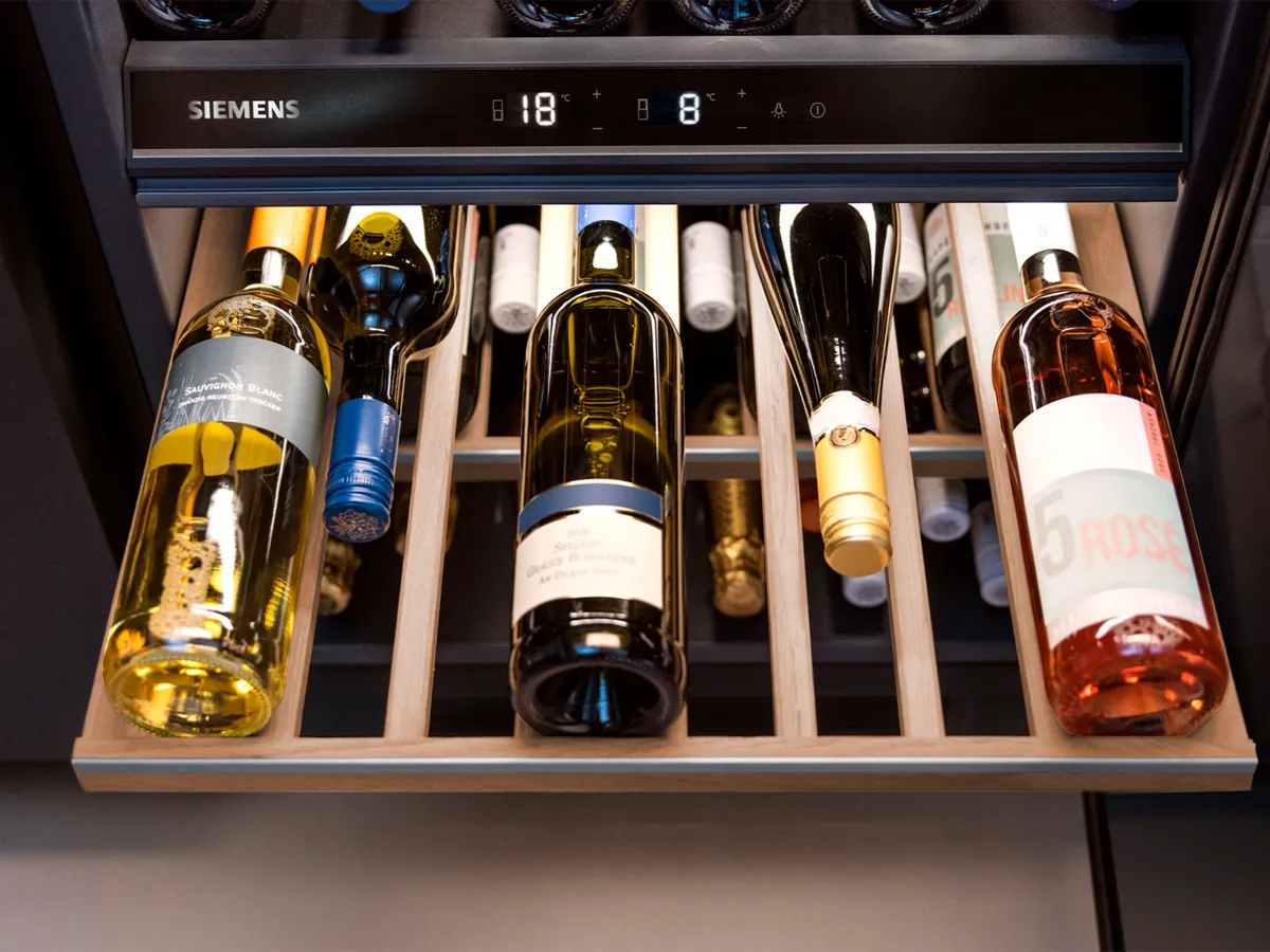 A wine cooler featuring an assortment of wine bottles, including Sauvignon Blanc and rosé, organized on wooden racks at specific temperatures.