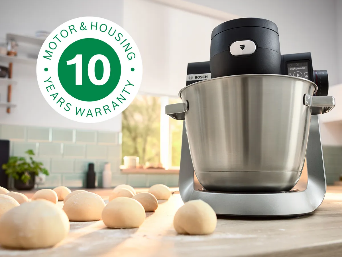 A imagem mostra o robô de cozinha Série 6 na bancada da cozinha ao lado de várias bolas de massa e com o logótipo de garantia de 10 anos sobreposto.