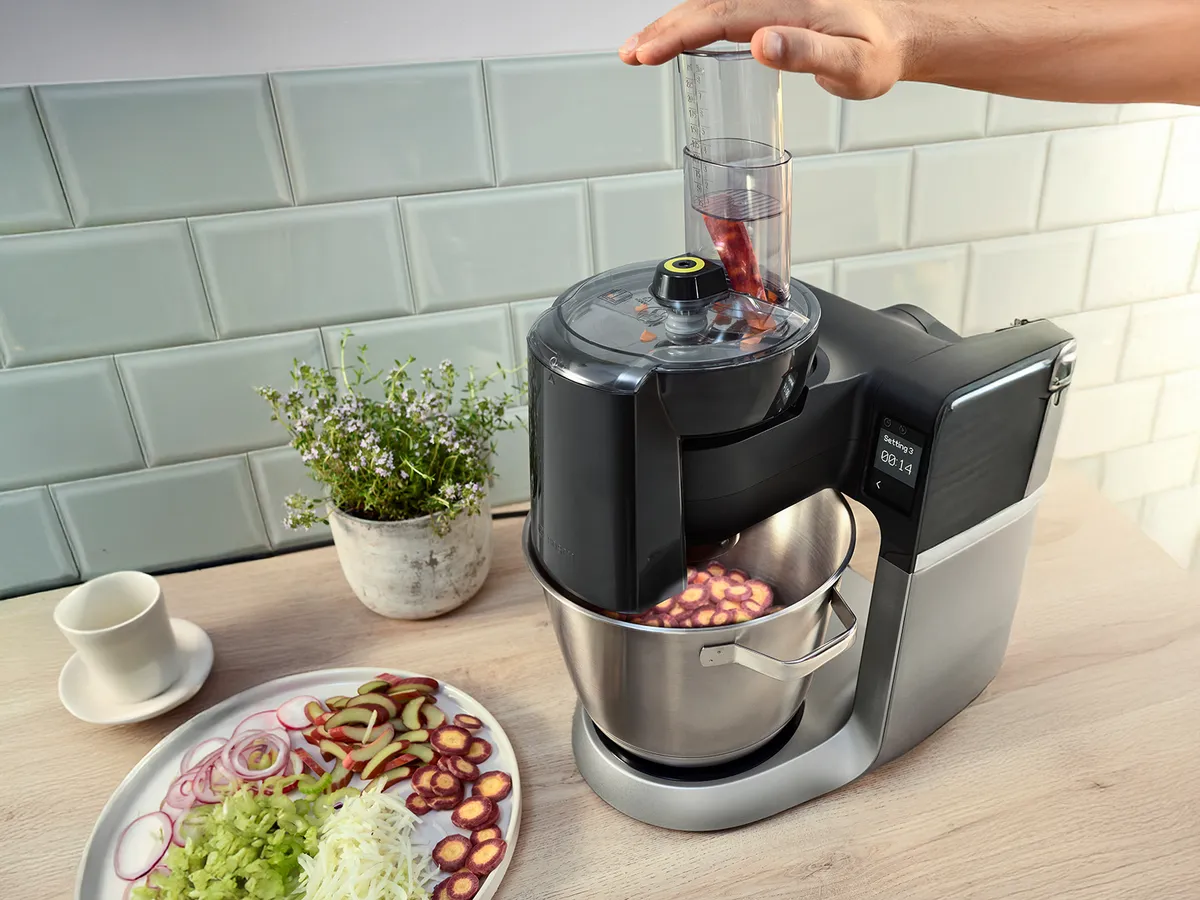 Robô de cozinha Série 6 com VeggieLove Set cortar malaguetas, colocadas ao lado de um prato com legumes fatiados e ralados.