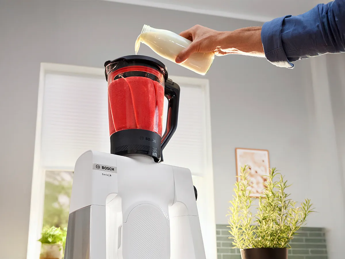 Robô Série 6 com o acessório misturador de vidro e o líquido a ser adicionado aos ingredientes vermelhos.
