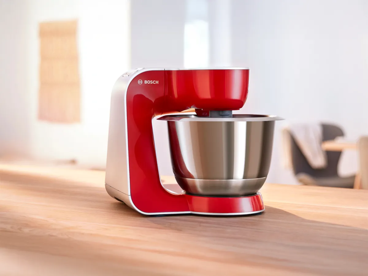 A red Bosch stand mixer on a kitchen counter. 