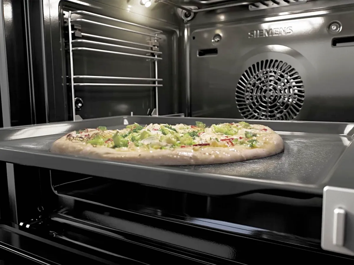 Pizza não cozinhada num tabuleiro dentro de um forno Siemens.