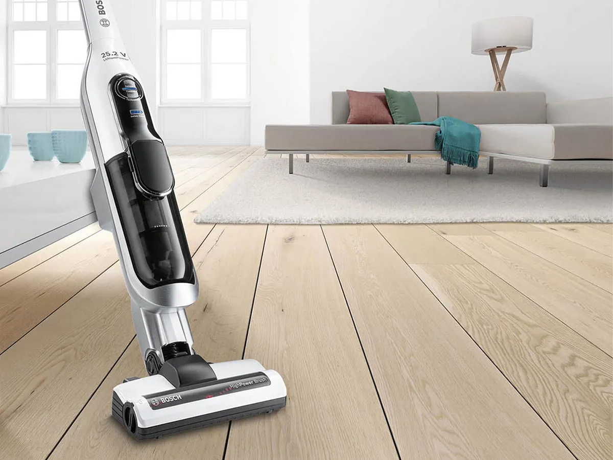 Ένας σκουπάκος Bosch Athlet στέκεται σε ένα σαλόνι. Υπάρχει ένας καναπές πίσω του.