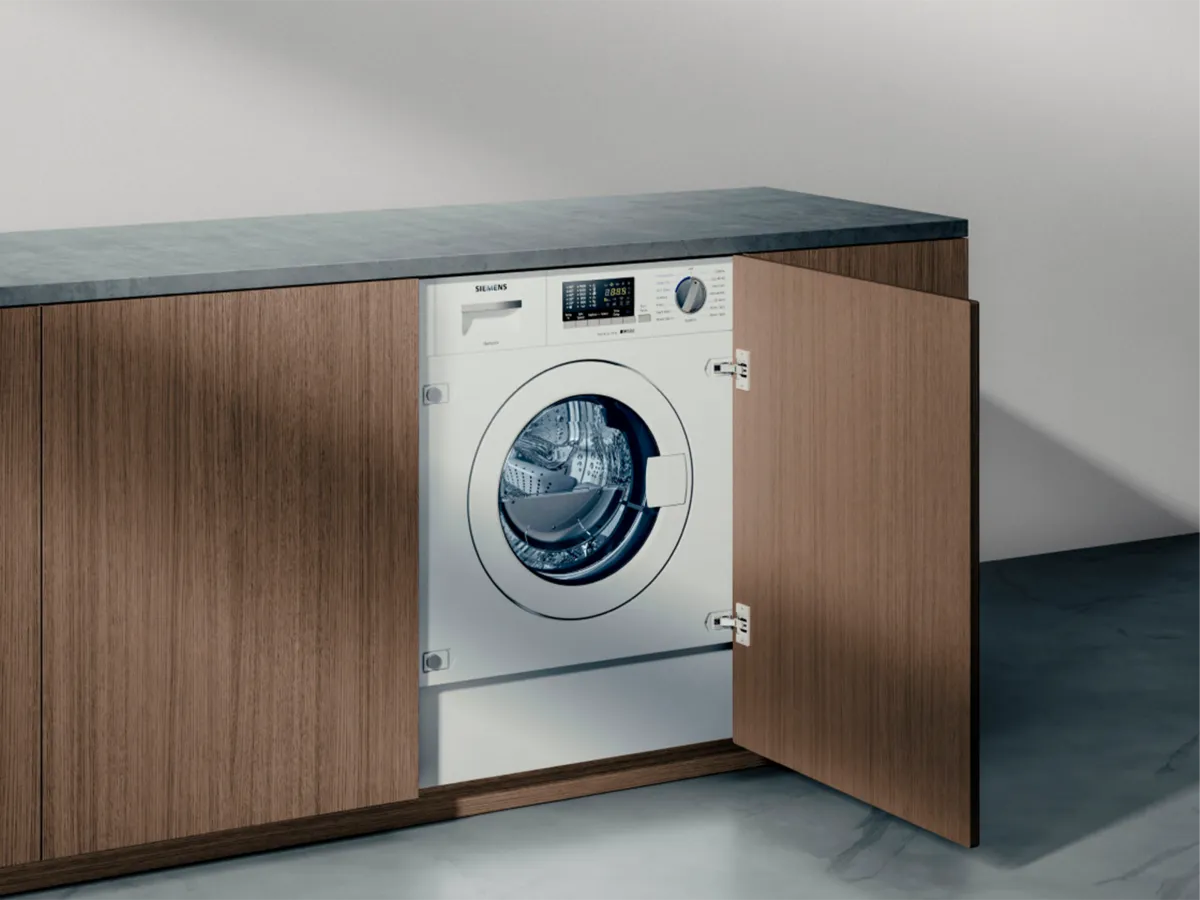 A modern washing machine built into wooden cabinetry with the door ajar.