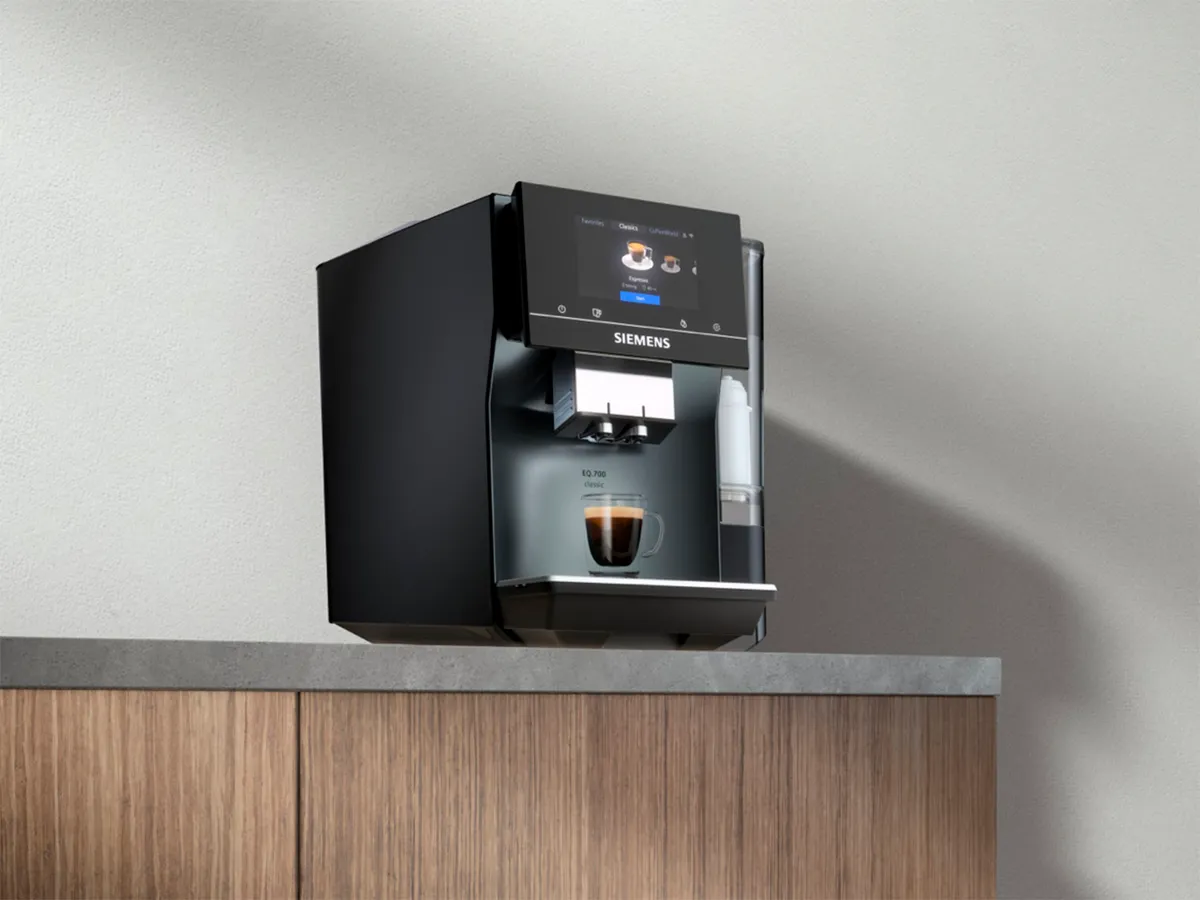 Siemens kaffemaskine dispenserer kaffe i en glaskop på et køkkenbord.