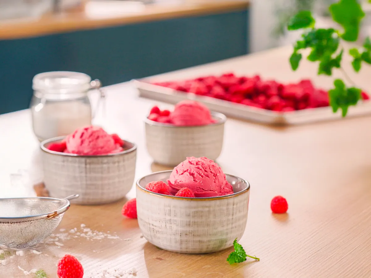 Gelado em taças sobre a bancada da cozinha, decorado com framboesas.