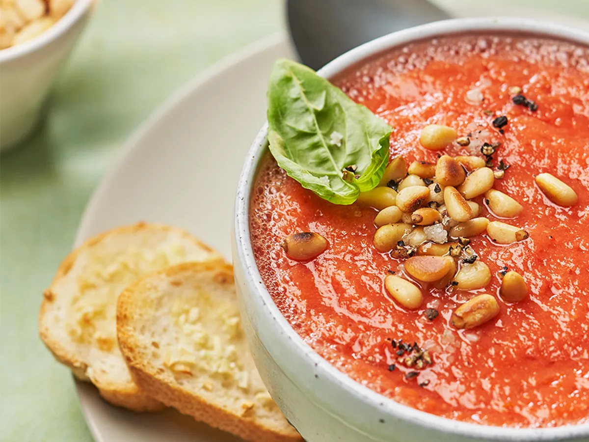 Small bowl of gazpacho garnished with pine nuts and basil. 