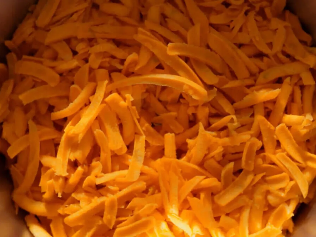 Top view of a cookit in which carrots are chopped.