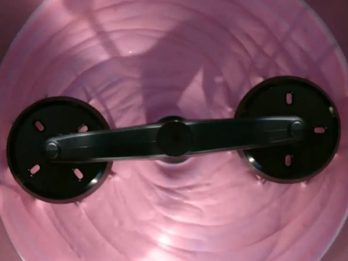 View from above of a cookit with purple creamy yoghurt that is being mixed and whipped with a mixer attachment.