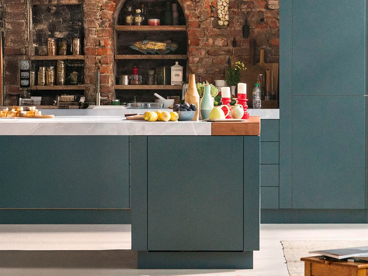 Modern kitchen with blue cabinets, exposed brick wall, and a rustic arched shelf filled with decor.