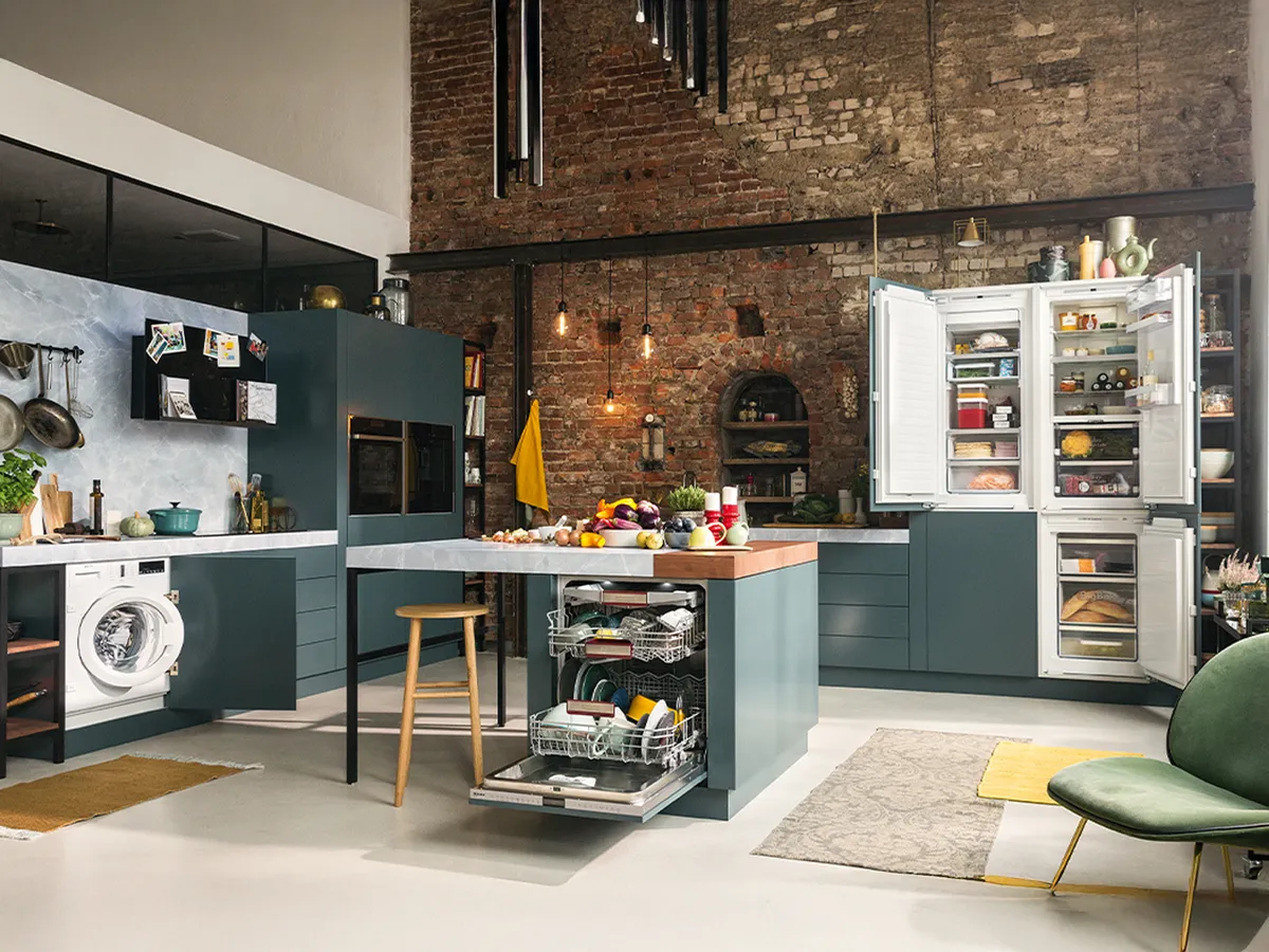 Weitblick auf industrielle L-Küche mit Kücheninsel und mehreren Geräten in der Mitte