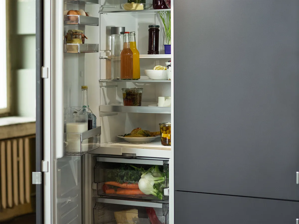 A built-in open fridge-freezer combination to the right of a large window.