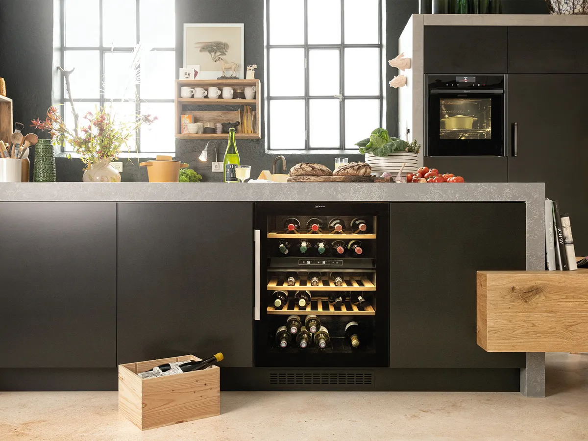 A wine cooler integrated in the kitchen island of a grey kitchen.