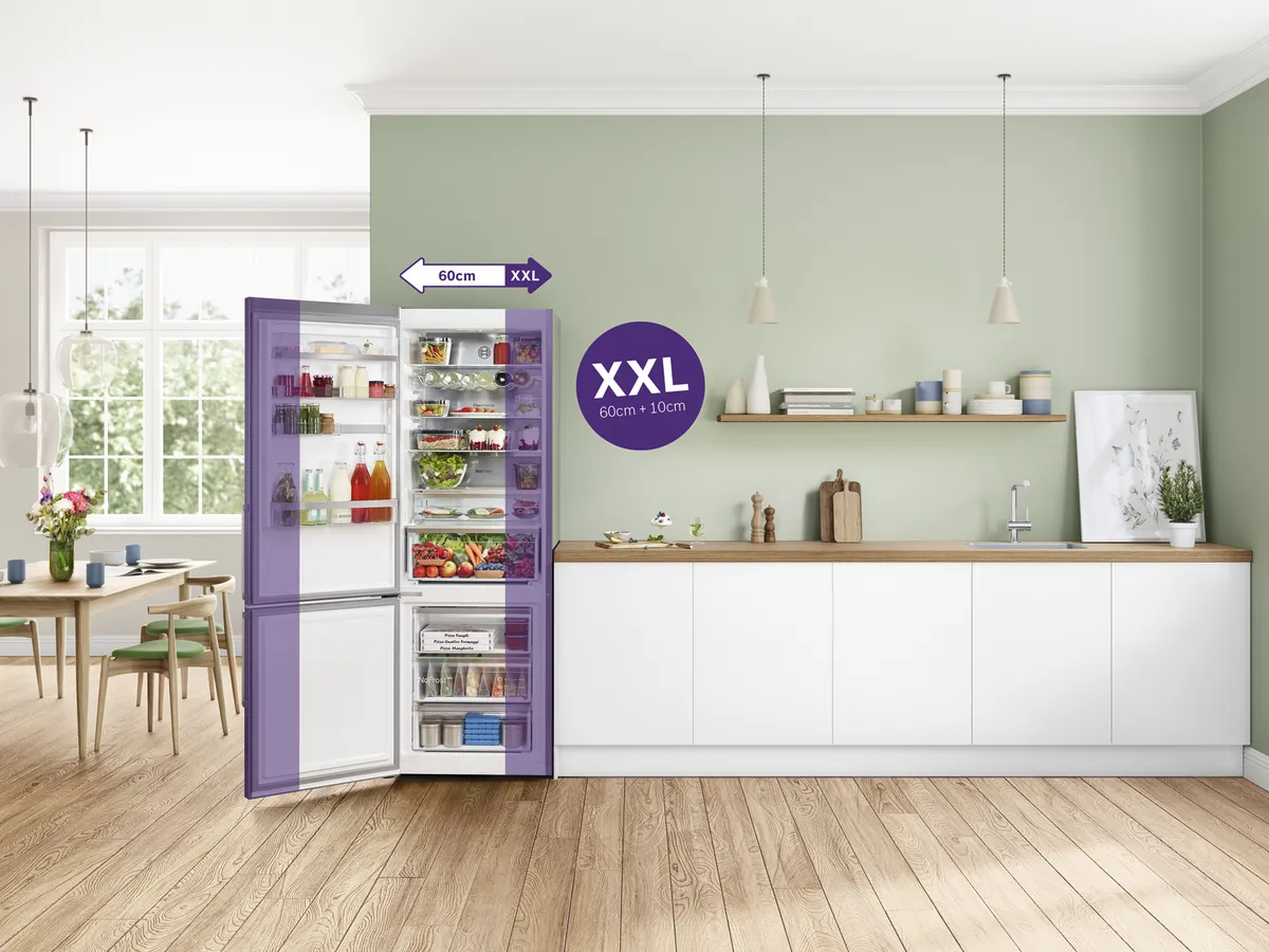 Uma cozinha moderna apresenta um frigorífico espaçoso preenchido com alimentos, marcado como tamanho XXL, contra uma parede verde-clara.