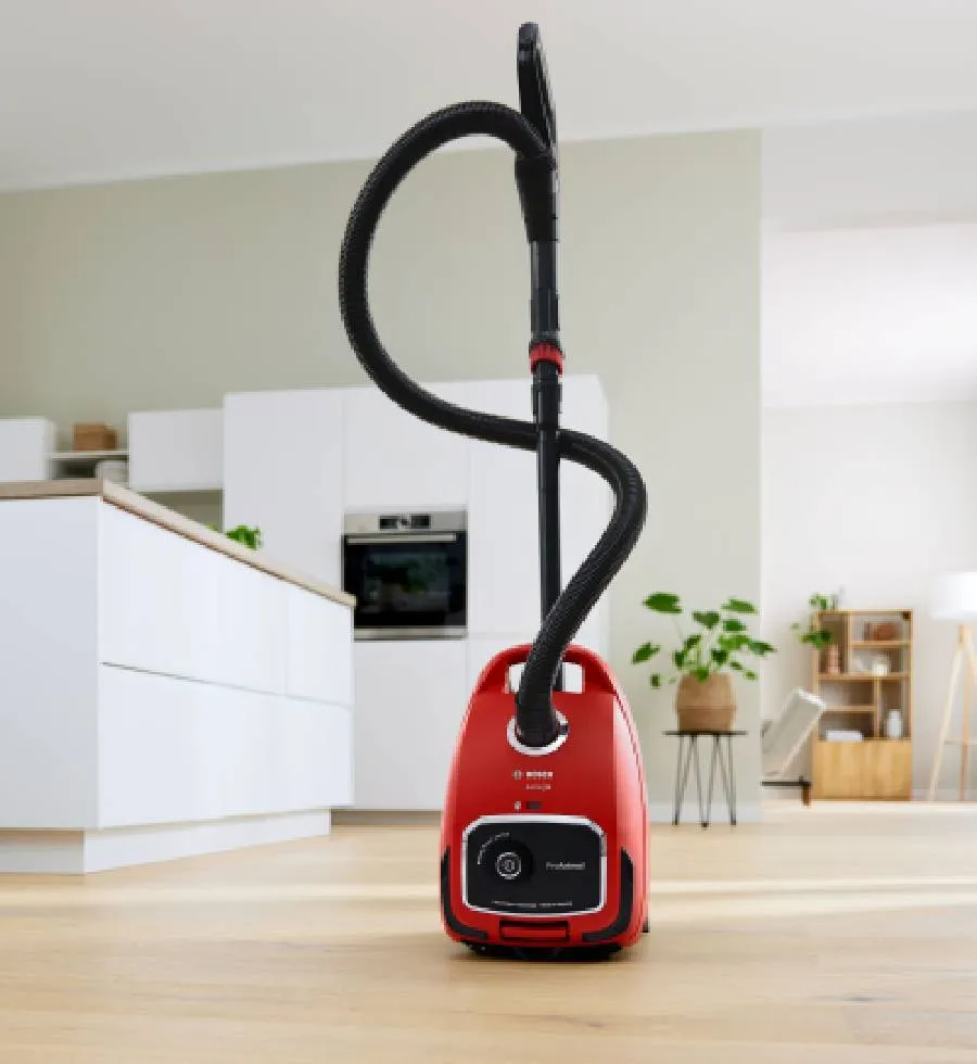 Un aspirapolvere a cilindro con sacco aspira lo sporco visibile sul pavimento.