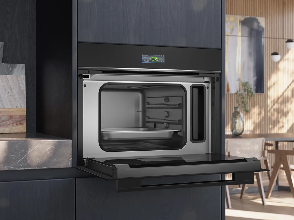 Um forno de encastrar elegante com uma porta aberta, que apresenta um interior espaçoso em aço inoxidável, num ambiente de cozinha moderno.