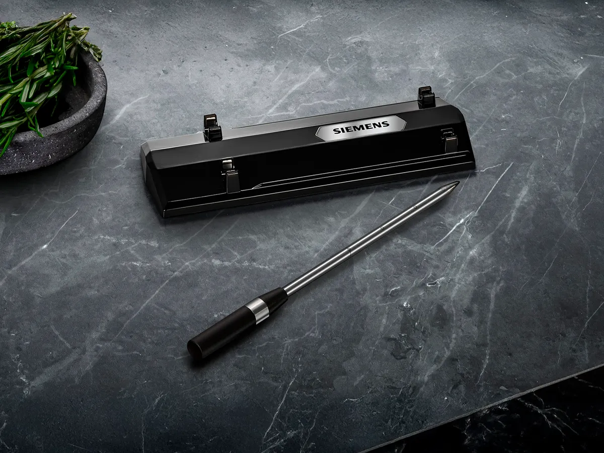 En Siemens trådlös roastingSensor och dess laddningsstation placerade på en grå marmorarbetskiva.