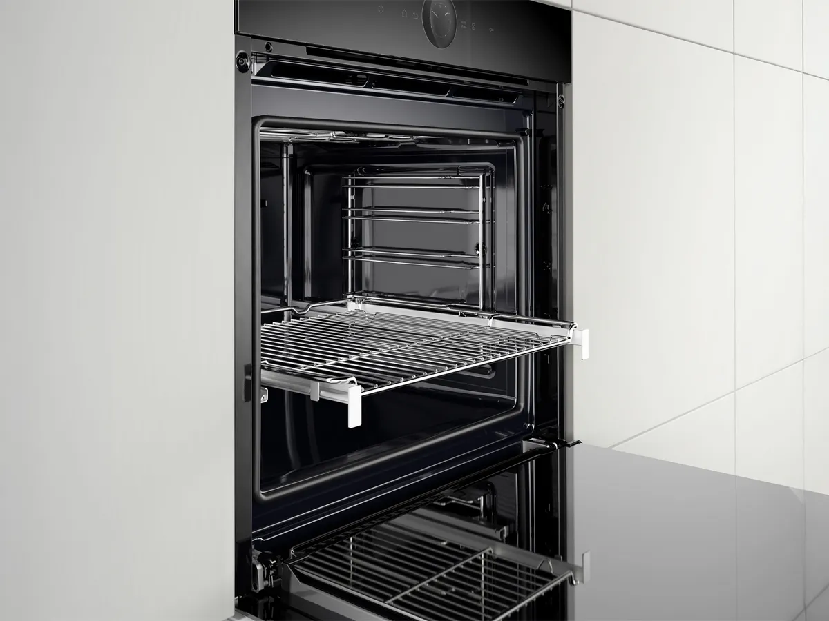 Um forno preto aberto com uma grelha de arame cromada e um design elegante.
