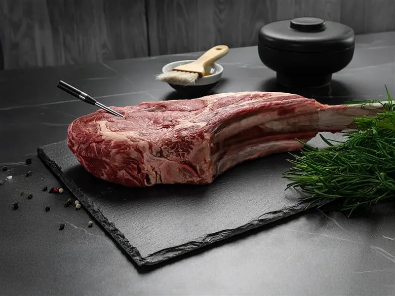En okokt T-bone-steak på en köksbänk med den trådlösa roastingSensor insatt.