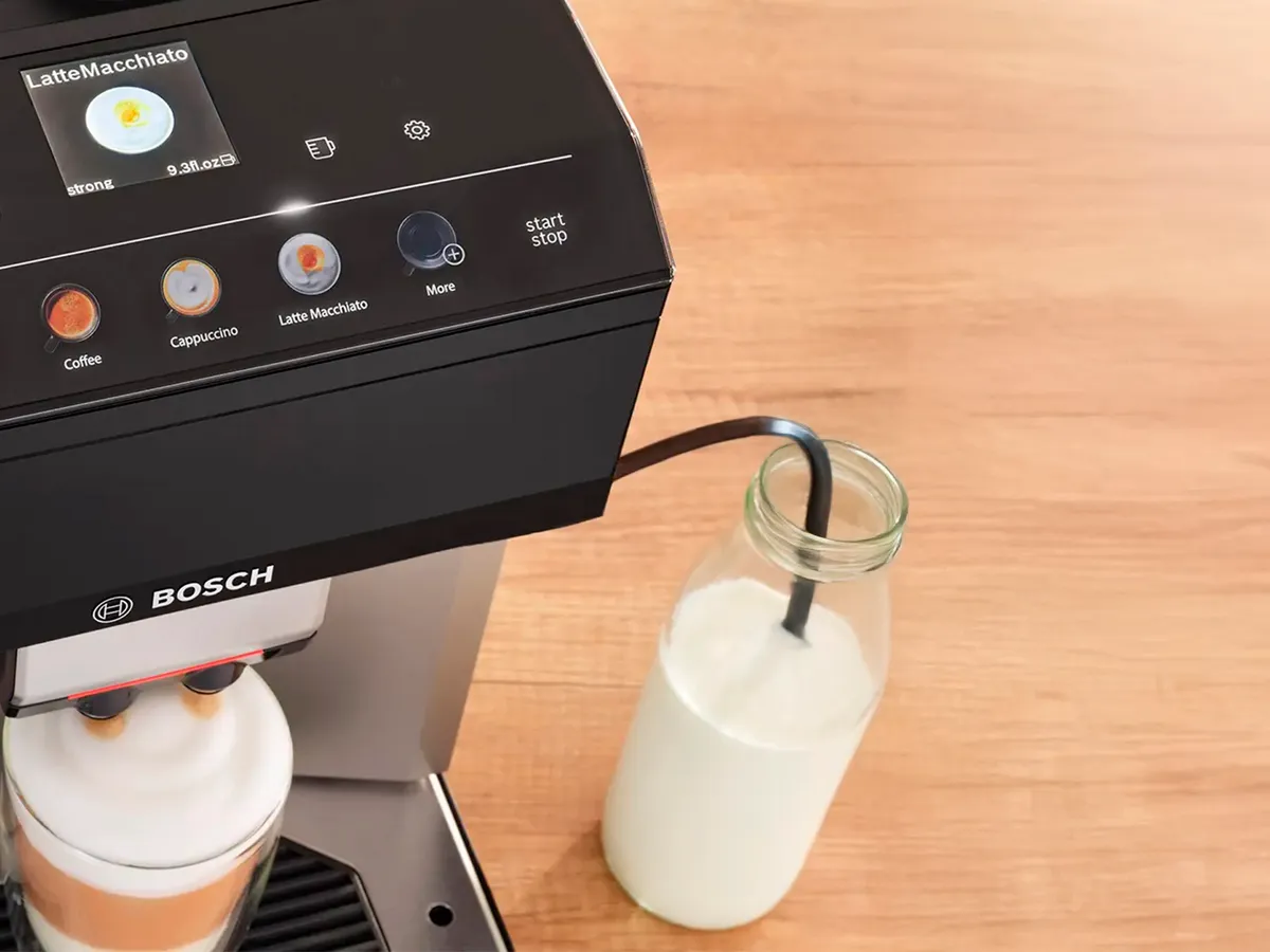 Vista de pássaro do ecrã Comfort Select da máquina de café VeroCafe e uma chávena de latte macchiato.
