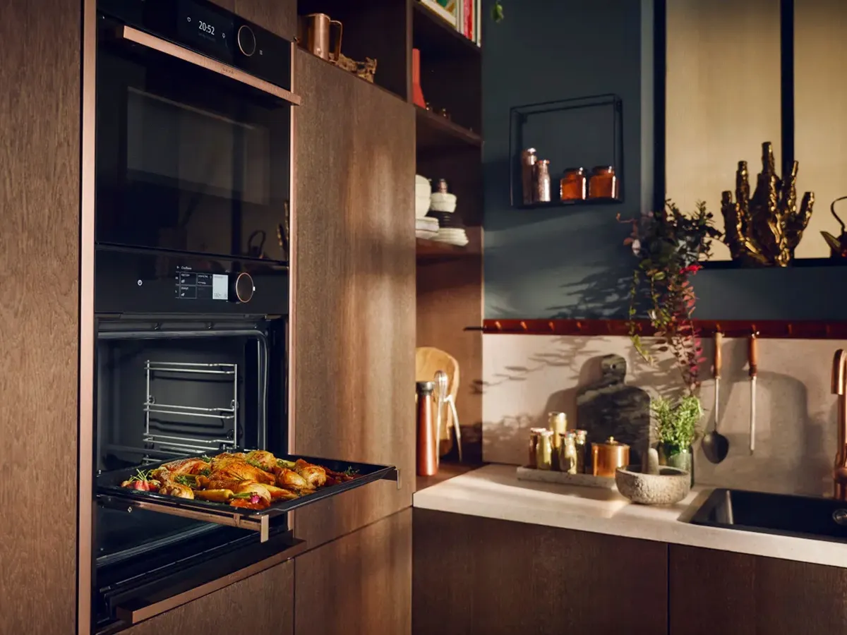 Die moderne Küche verfügt über einen eingebauten Ofen mit einem Tablett mit gebratenem Huhn und Gemüse, umgeben von stilvollen Holzschränken und Dekor.