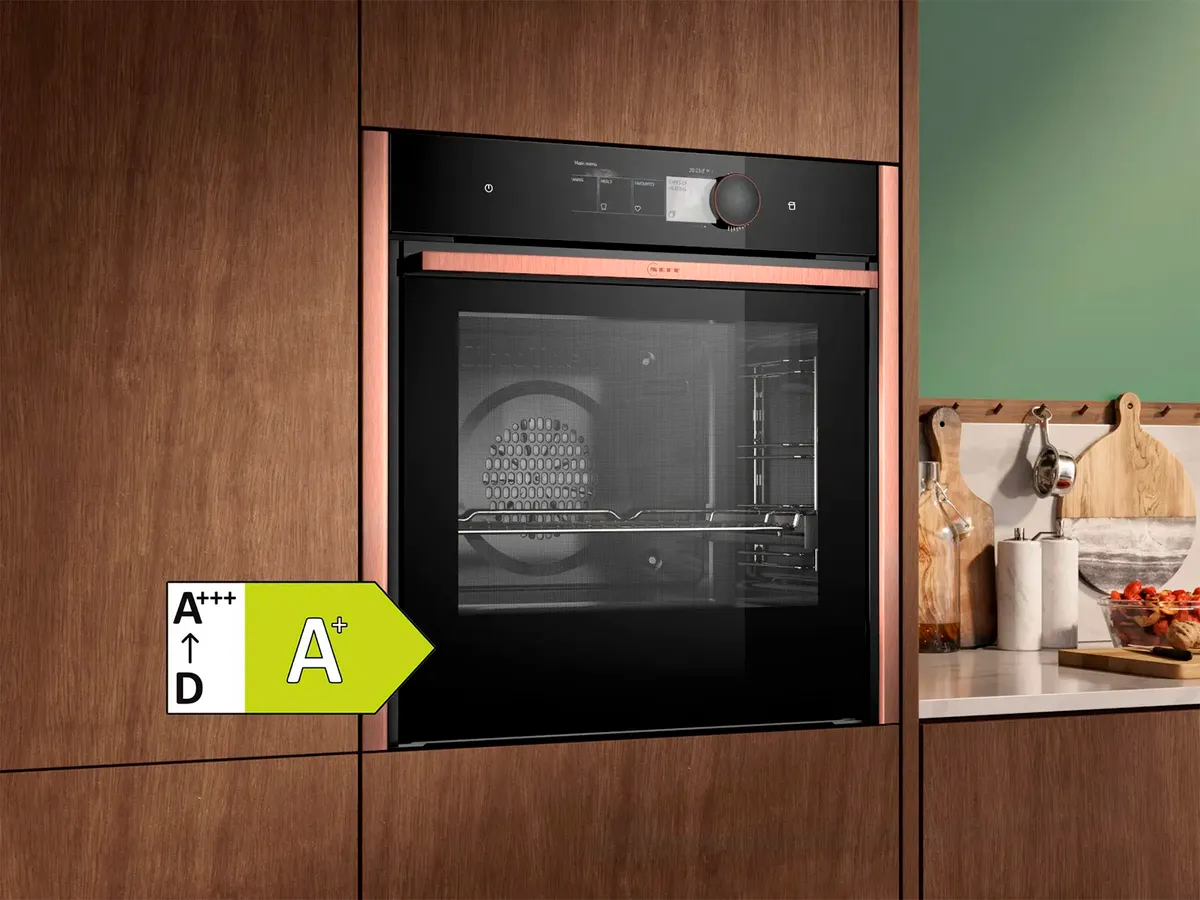 Modern oven built into wooden cabinets with black glass front and energy efficiency class A+. The kitchen equipment includes various utensils.