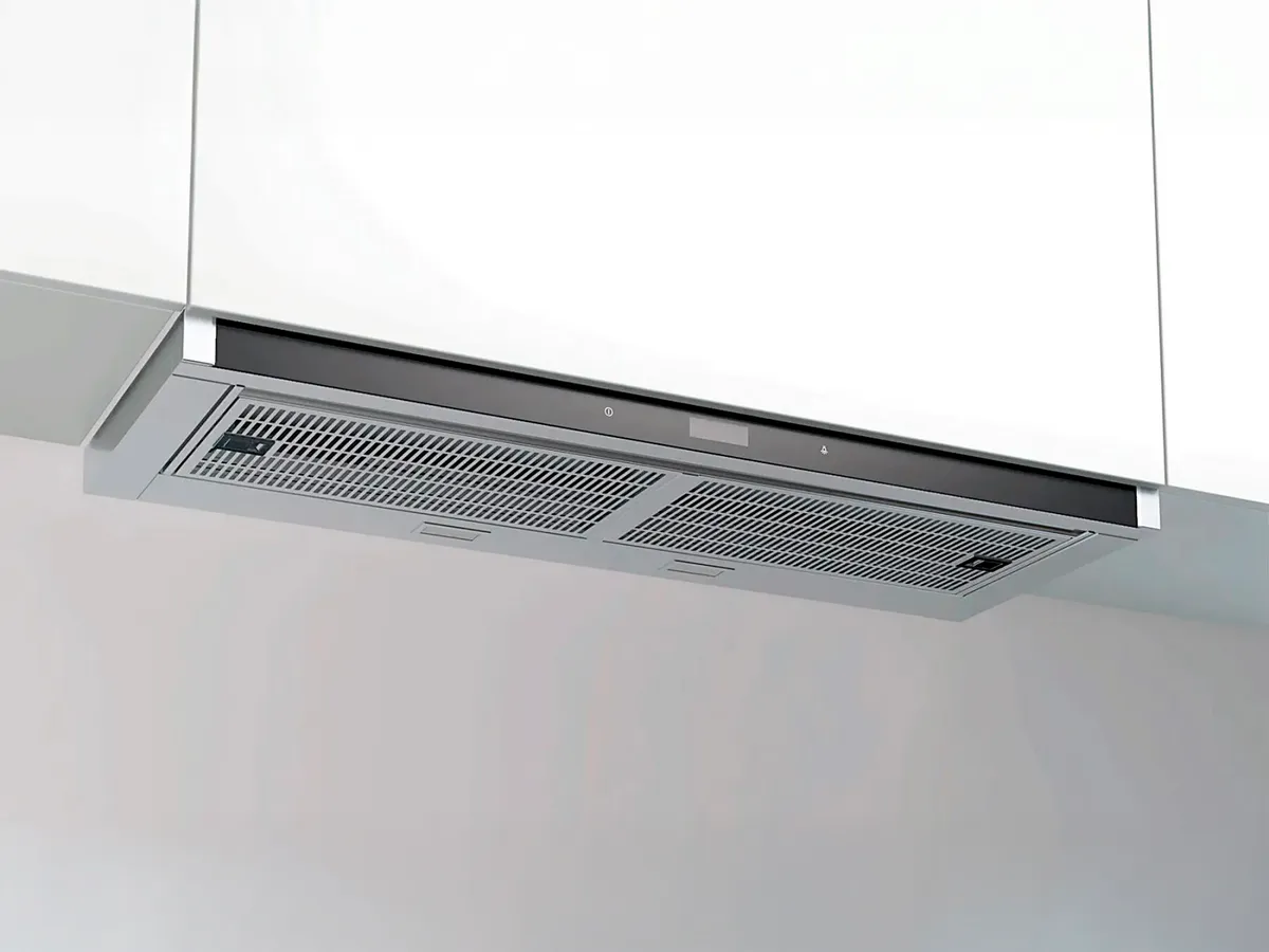 Eine elegante, moderne Edelstahl-Dunstabzugshaube mit Netzfilter, installiert unter einem weißen Schrank.