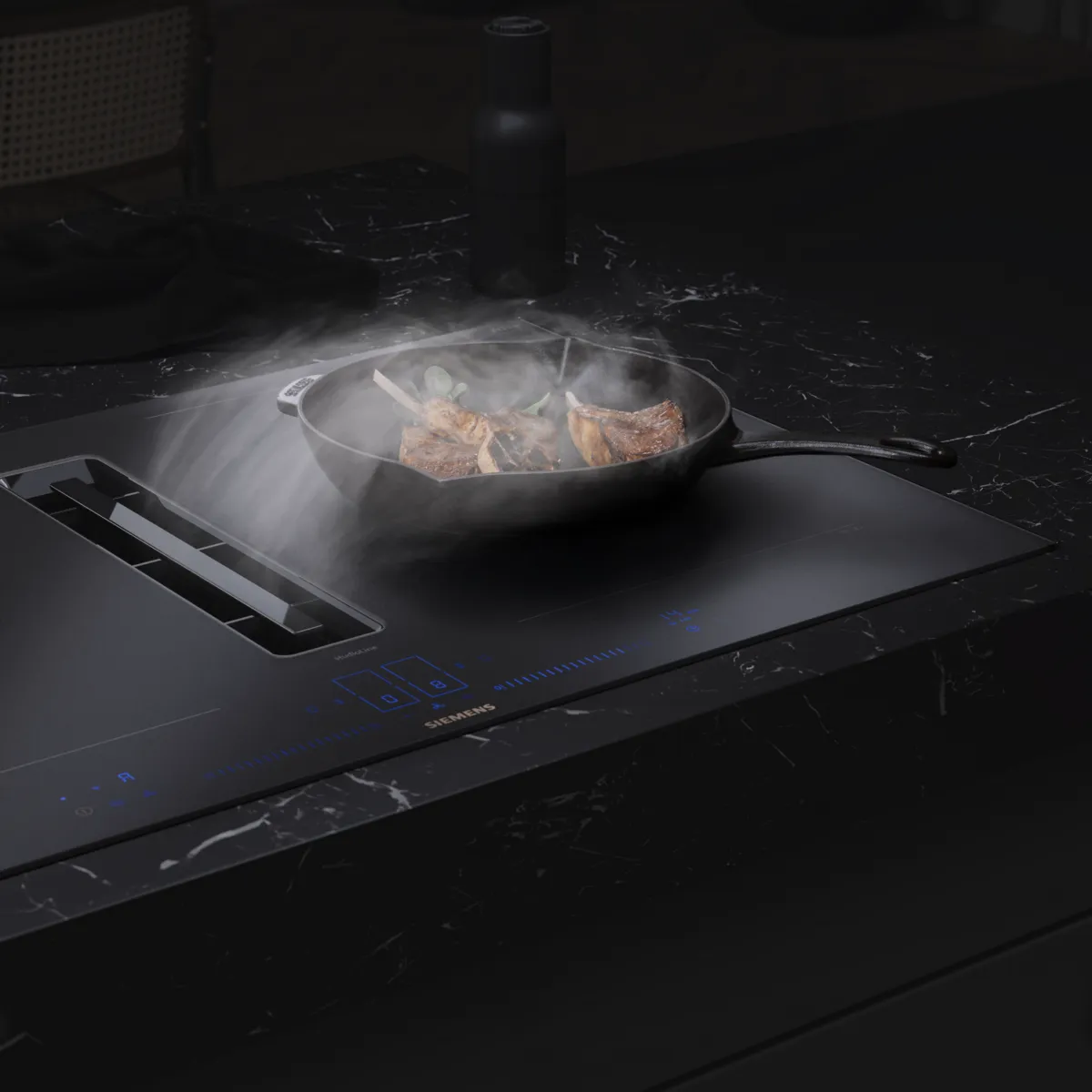 Een kookplaat met geïntegreerde afzuiging in matte afwerking en rook uit de pan met vlees en groenten.
