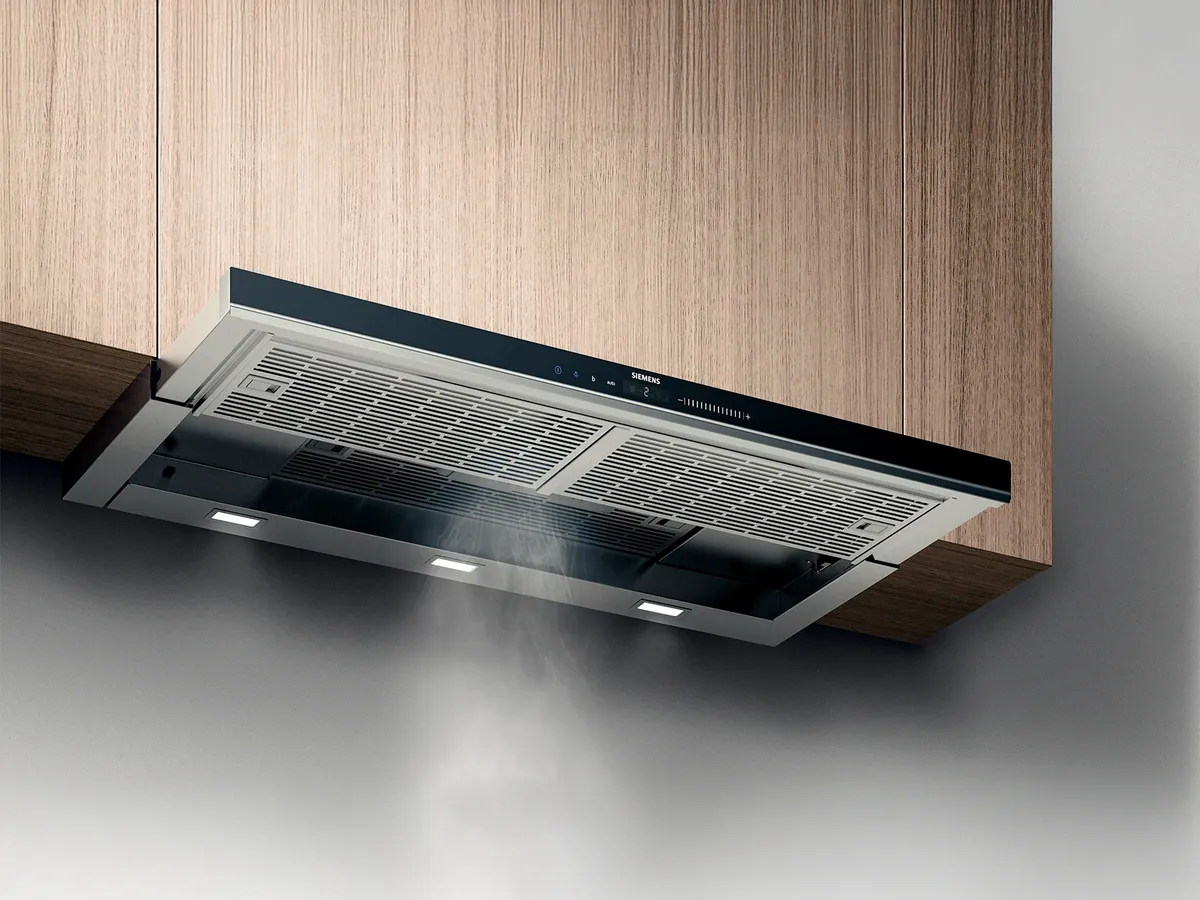 Uma chaminé Siemens elegante e moderna instalada sob armários de madeira, com fumaça subindo e luzes LED iluminando a área abaixo.