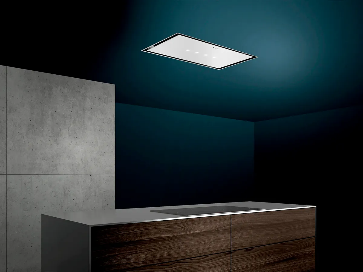 Cozinha moderna com uma elegante ilha de madeira, fogão de indução e uma chaminé minimalista montada no teto contra uma parede azul escura.