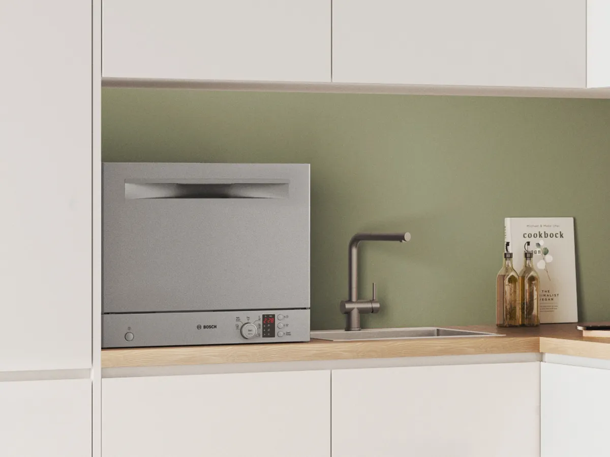 A modern kitchen corner featuring a Bosch dishwasher, minimalist sink, and a cookbook.