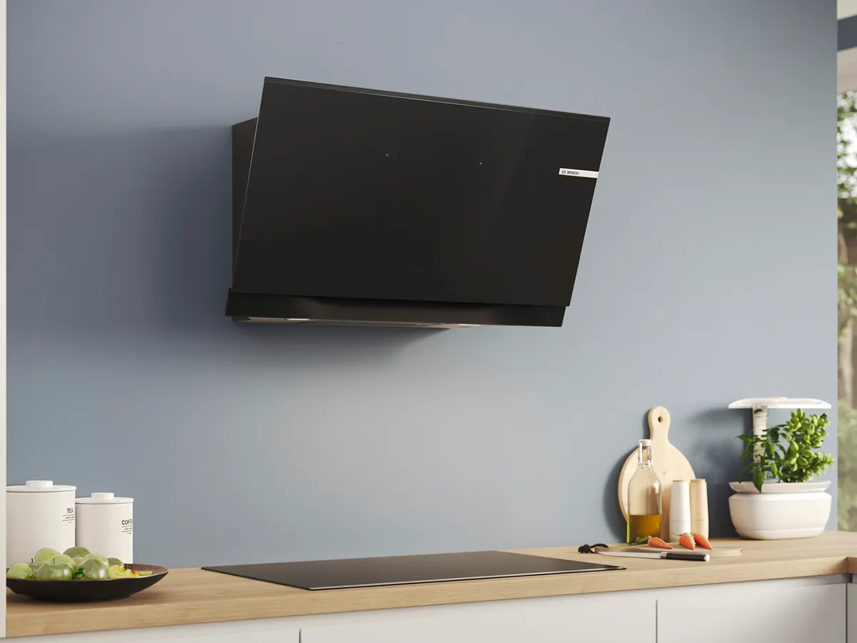 Uma cozinha moderna com uma elegante exaustor de parede preto, armários minimalistas e um balcão.
