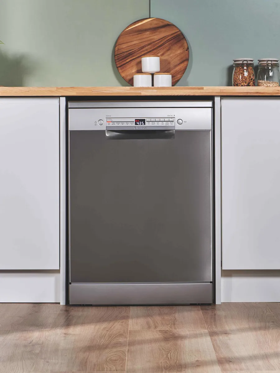 Closed dishwasher under a counter in green kitchen