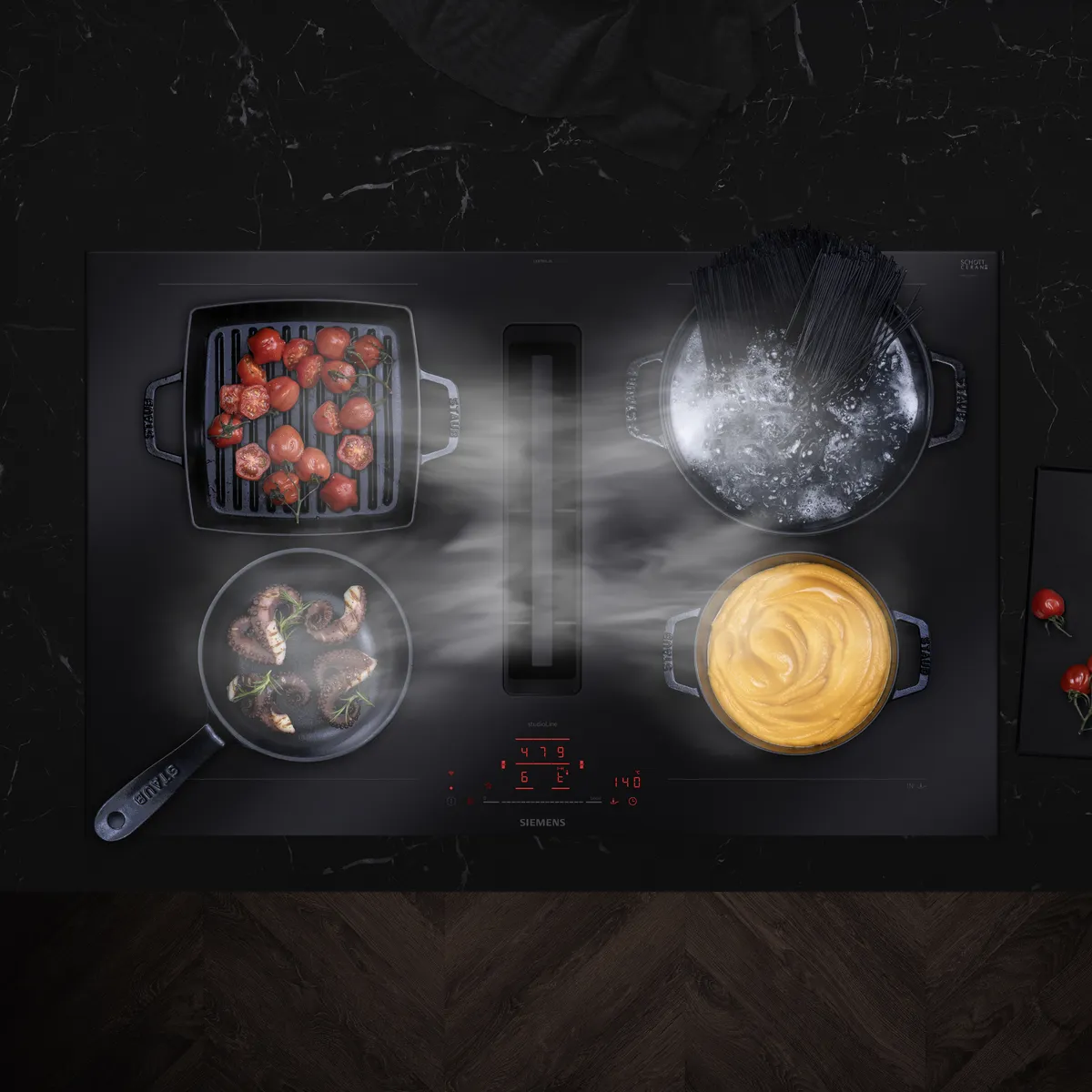 Siemens-Herd mit mehreren Gerichten, die kochen: Tomaten, Pasta, Fleisch und Sauce auf einer schwarzen Oberfläche.