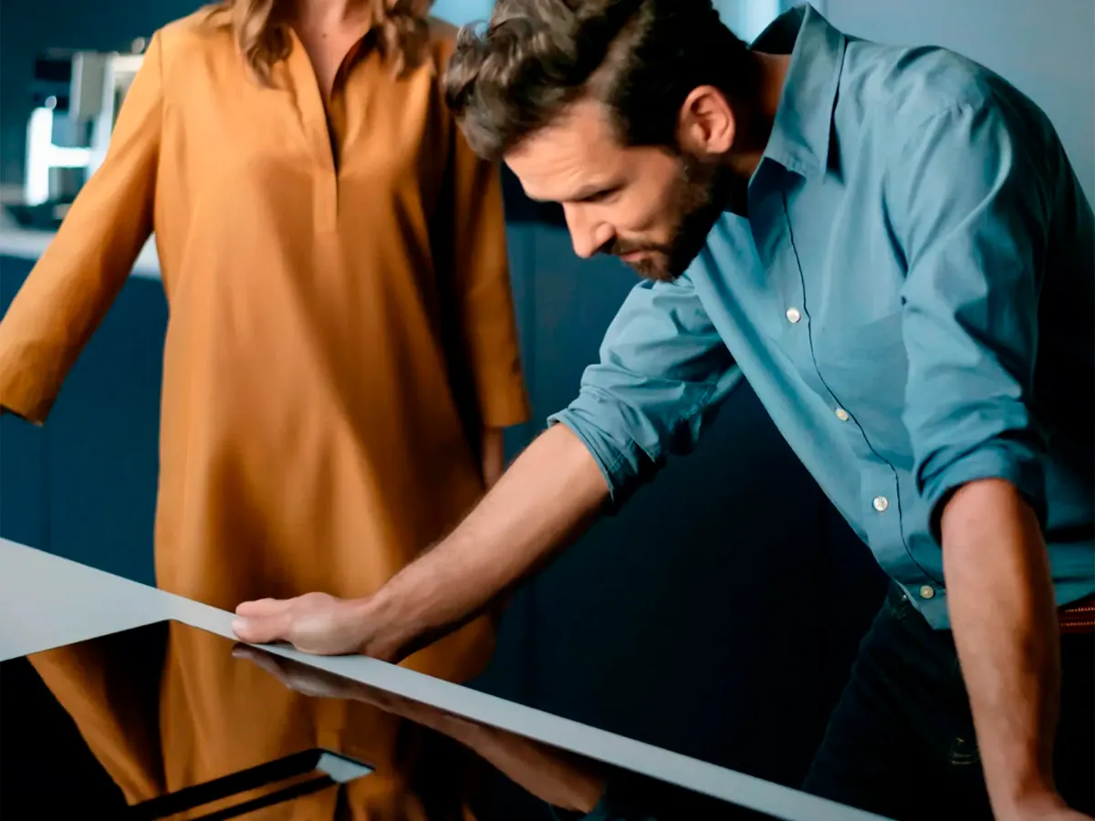 A man leaning over a Siemens induction hob and a woman standing in the background.
