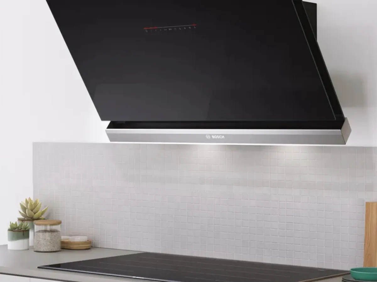 Modern kitchen featuring a sleek black wall-mounted range hood, minimalist cabinetry, and a countertop.