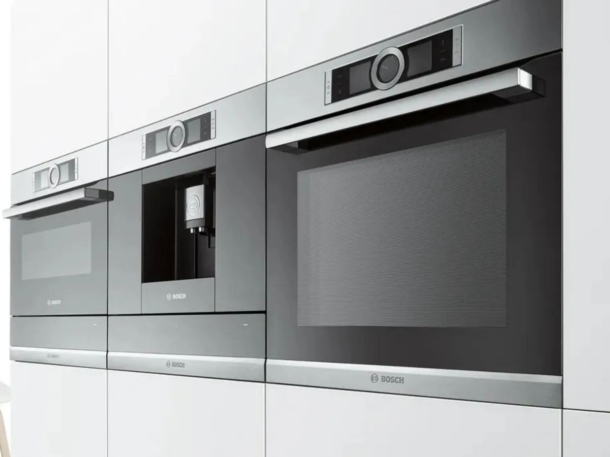 A modern kitchen with black cabinetry featuring built-in appliances and a plate of salmon with vegetables.