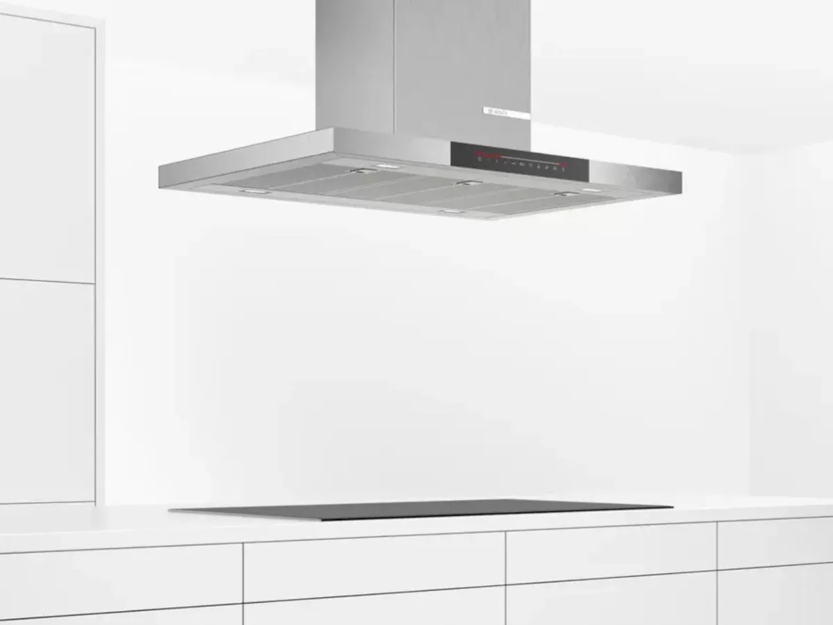 Modern kitchen featuring a stylish hood above a wooden island, with a pot and fruit bowl.