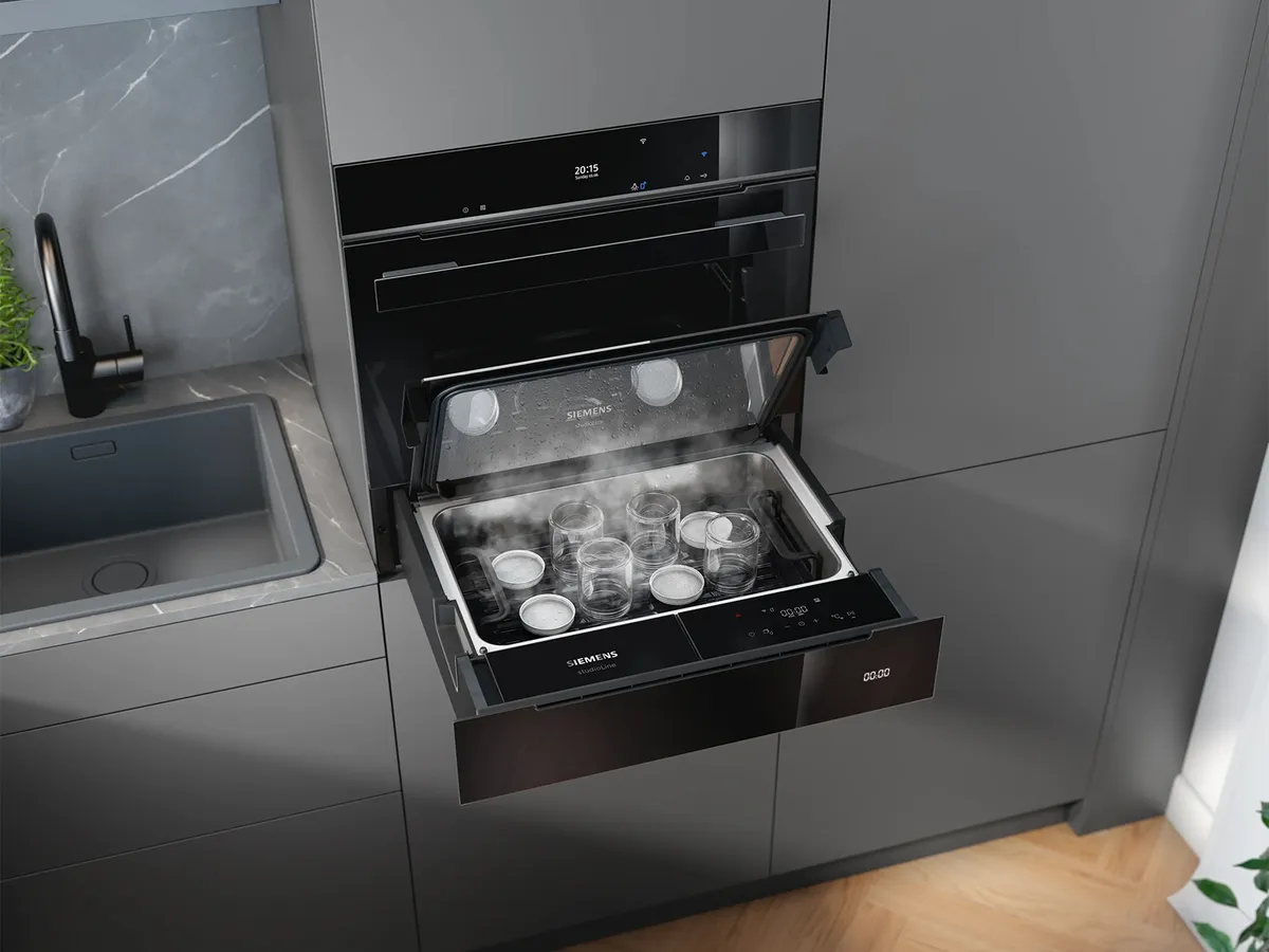 Siemens Wärmeschublade mit offenem Dampfofen, der dampfende Gläser in einer modernen Küche zeigt.